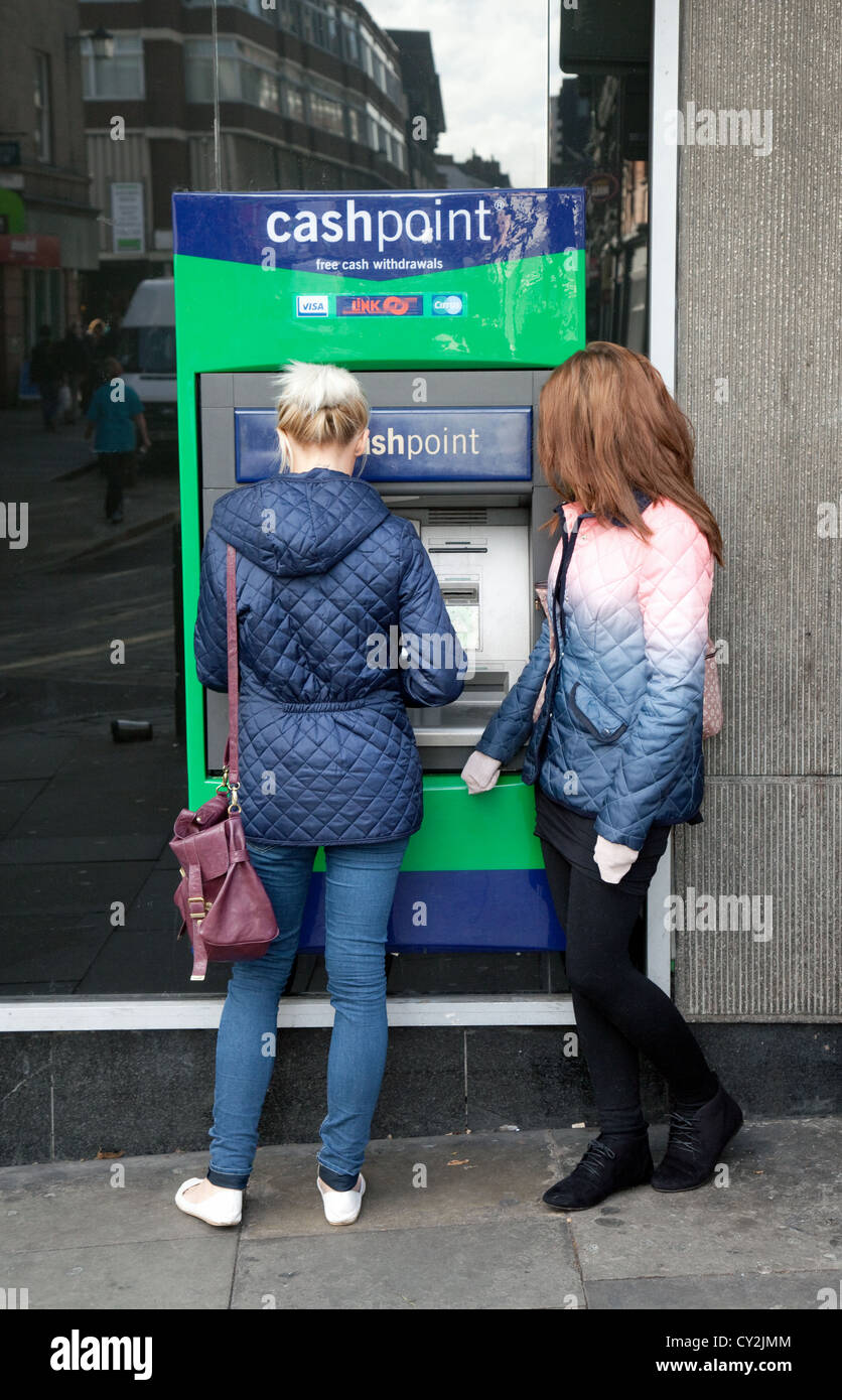 Due adolescenti ottenere contanti presso la Lloyds TSB BANCOMAT, REGNO UNITO Foto Stock