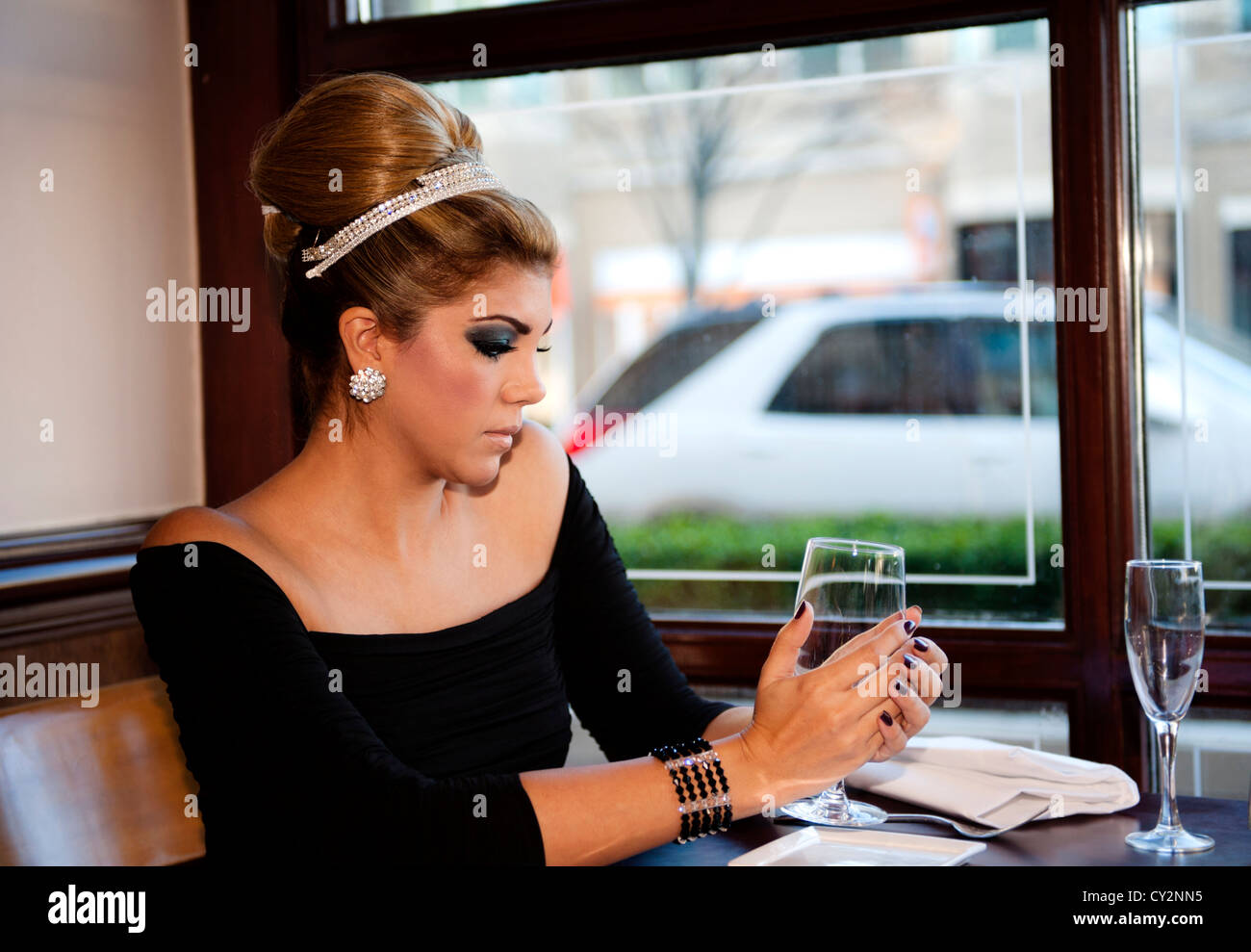 Una bella donna tenendo un bicchiere di vino in un nero abito da sera Foto Stock