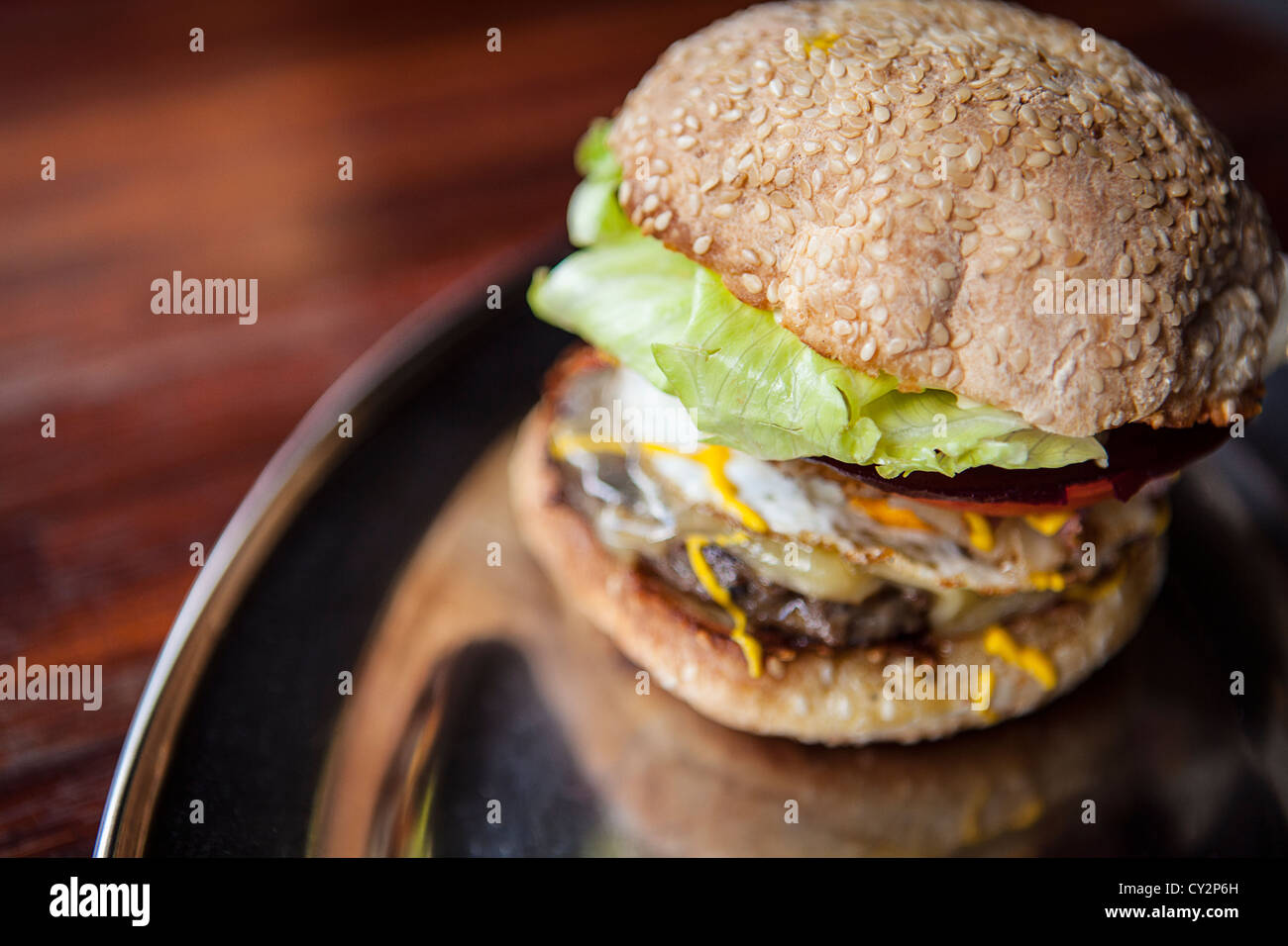 Primo piano di un formaggio hamburger con uova, senape e lattuga. Messa a fuoco selettiva; profondità di campo. Foto Stock
