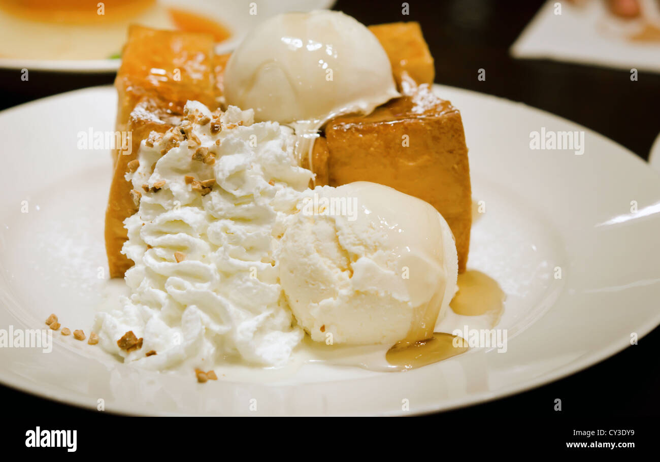 Toast con gelato ,la panna e sciroppo di miele sulla piastra bianca Foto Stock