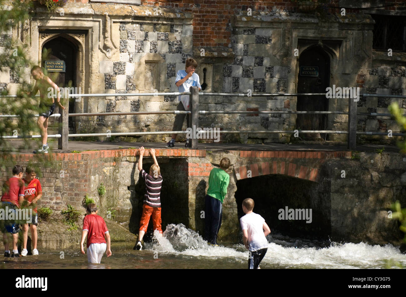 I bambini che giocano nel fiume di gara al di fuori della Old Mill House Hotel nel quartiere Harnham di Salisbury, Wiltshire, Regno Unito. Foto Stock