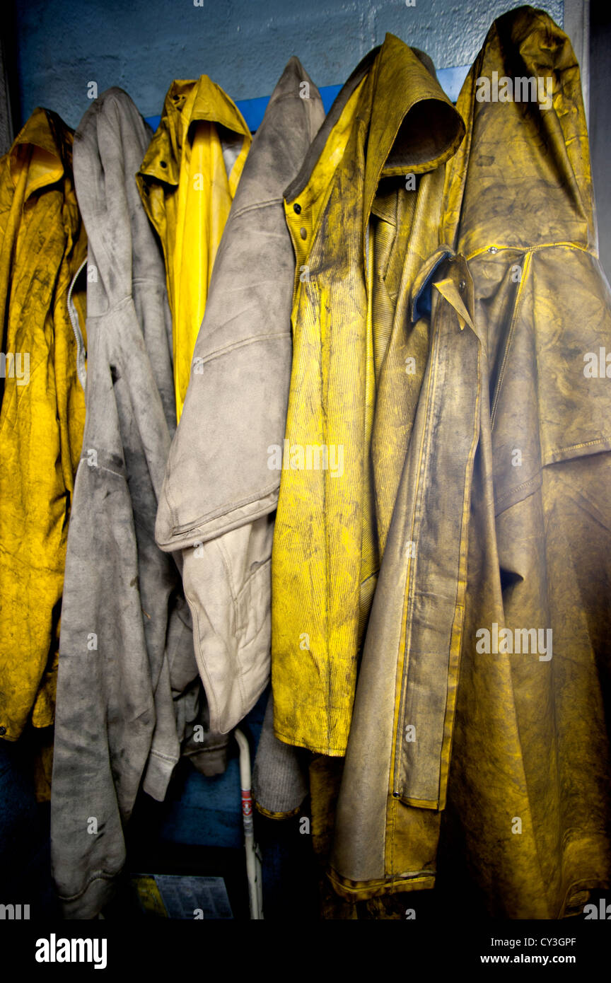 Protettivo giallo slickers pioggia utilizzati dai lavoratori in un impianto industriale. Foto Stock