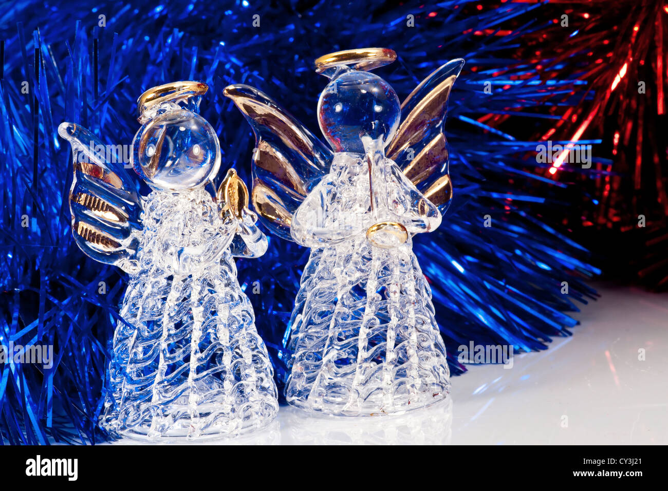 Due in vetro decorativo di angelo e di albero di Natale tinsel su bianco con riflessioni Foto Stock