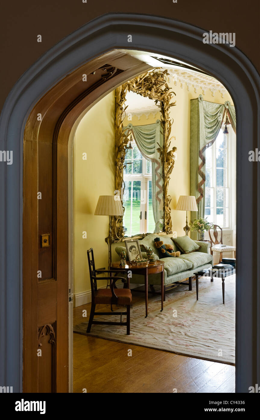 Vista attraverso il portale ad arco in un disegno di colore giallo-room con antichi gilt incorniciato specchio francese Foto Stock