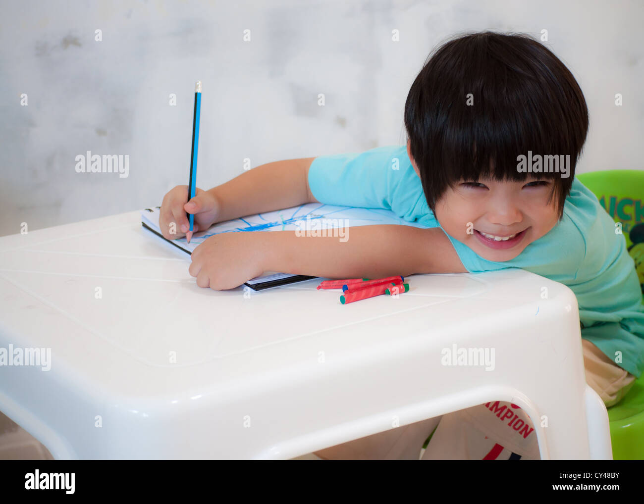 Ragazzo con pittura a matita su un libro di disegno. Foto Stock
