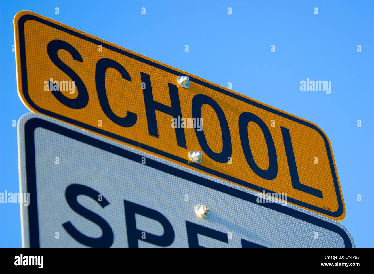 Segnale di limite di velocità con la scuola speciale un avviso in giallo contro il cielo blu. S e C sono leggermente fuori fuoco. è messa a fuoco al centro Foto Stock