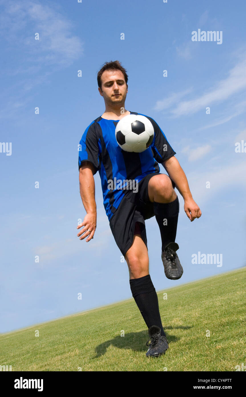 Calcio - giocatore di football Juggling in blu e nero uniforme Foto Stock