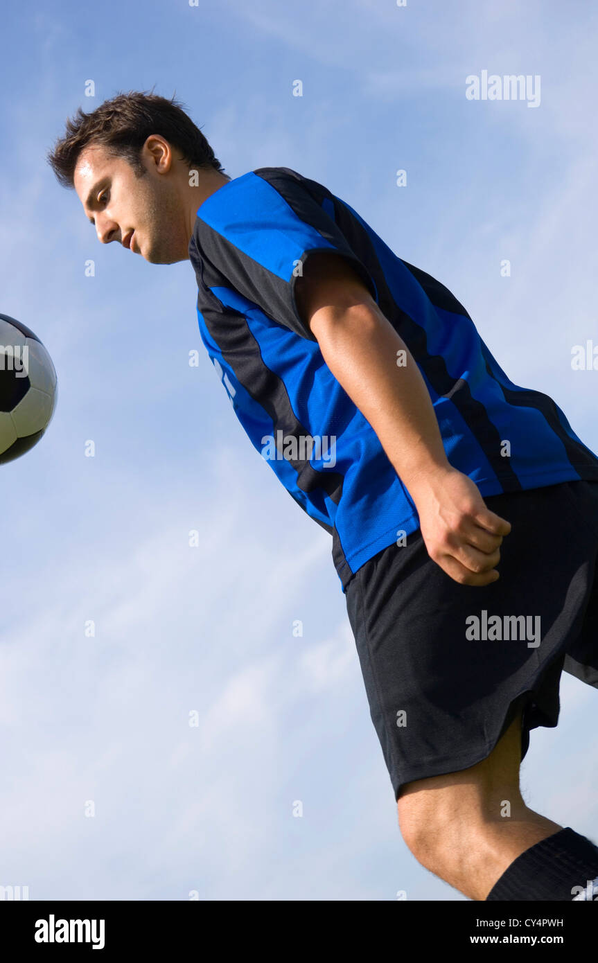 Calcio - giocatore di football Juggling in blu e nero uniforme Foto Stock