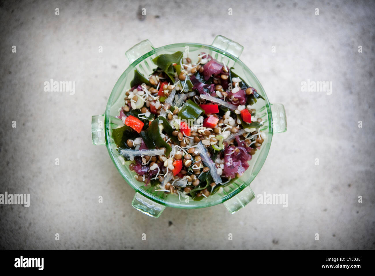 Tettuccio di colpo di un insalata di alghe marine e germinazione i fagioli in una terrina verde shot su una pietra grigia sullo sfondo Foto Stock