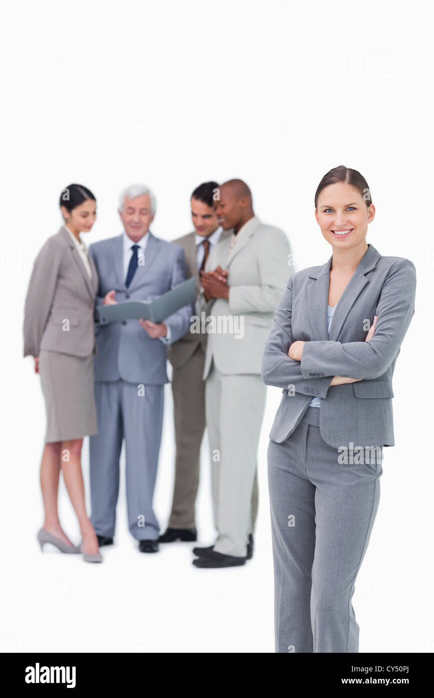 Tradeswoman sorridente con le braccia incrociate e il team dietro di lei Foto Stock