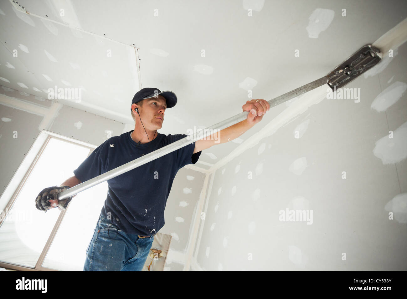 Stati Uniti d'America, Utah, Lehi, lavoratore di muretti a secco con l'applicazione del nastro ad angolo tra la parete e il soffitto Foto Stock