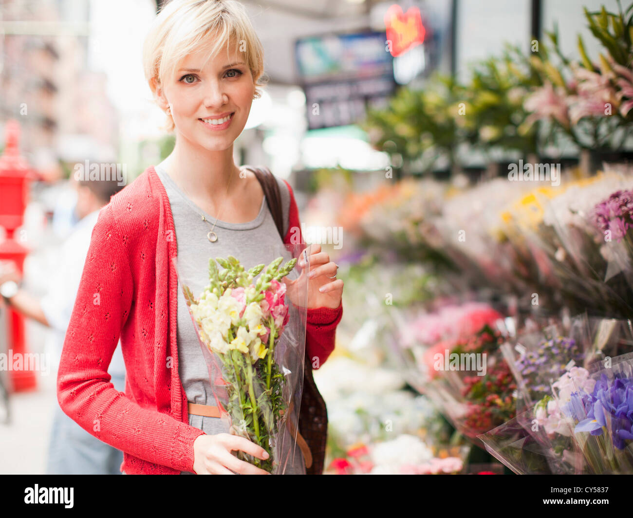 Stati Uniti d'America, nello Stato di New York, New York, ritratto di donna sorridente holding mazzo di fiori al di fuori del fioraio Foto Stock
