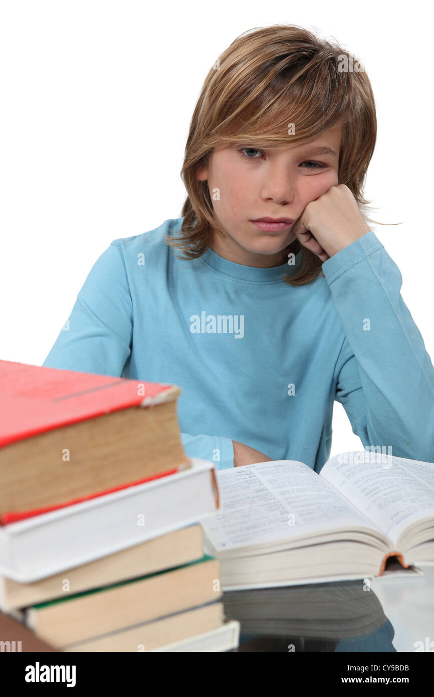 Un annoiato bambino la lettura di un libro Foto Stock