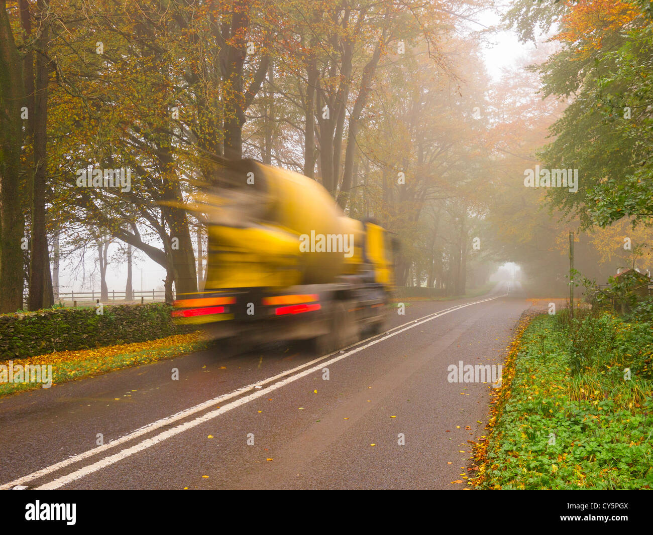 Una betoniera camion che viaggiano lungo una nebbia country road. Foto Stock