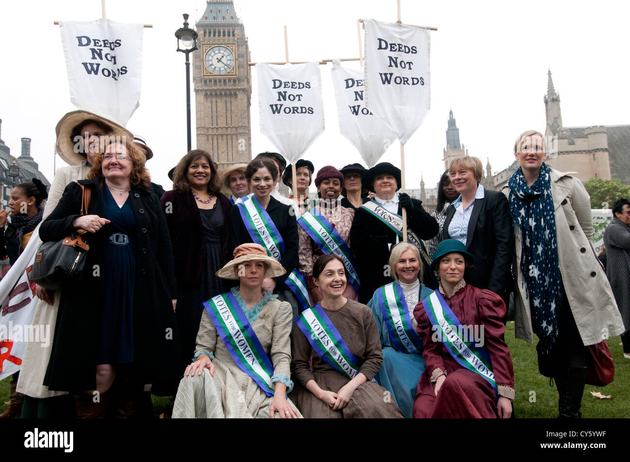 Donne abbigliate come suffragettes, tenendo striscioni dicendo "fatti non parole' sitted davanti a un gruppo di donne parlamentari Foto Stock