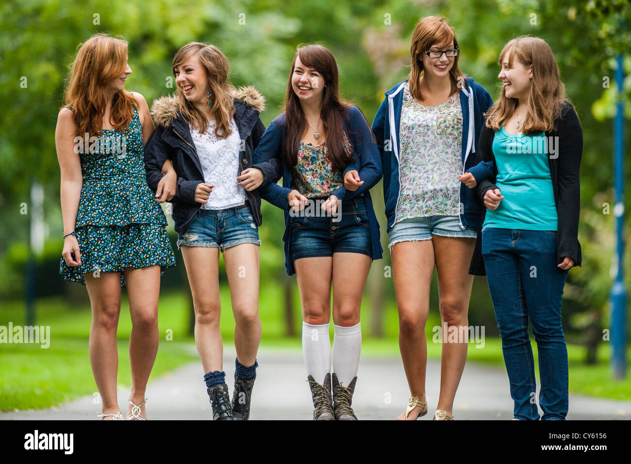 Un gruppo di cinque 5 giovane adolescente inglese britannico welsh teen ragazze adolescenti amici camminando insieme a braccetto esterno REGNO UNITO Foto Stock
