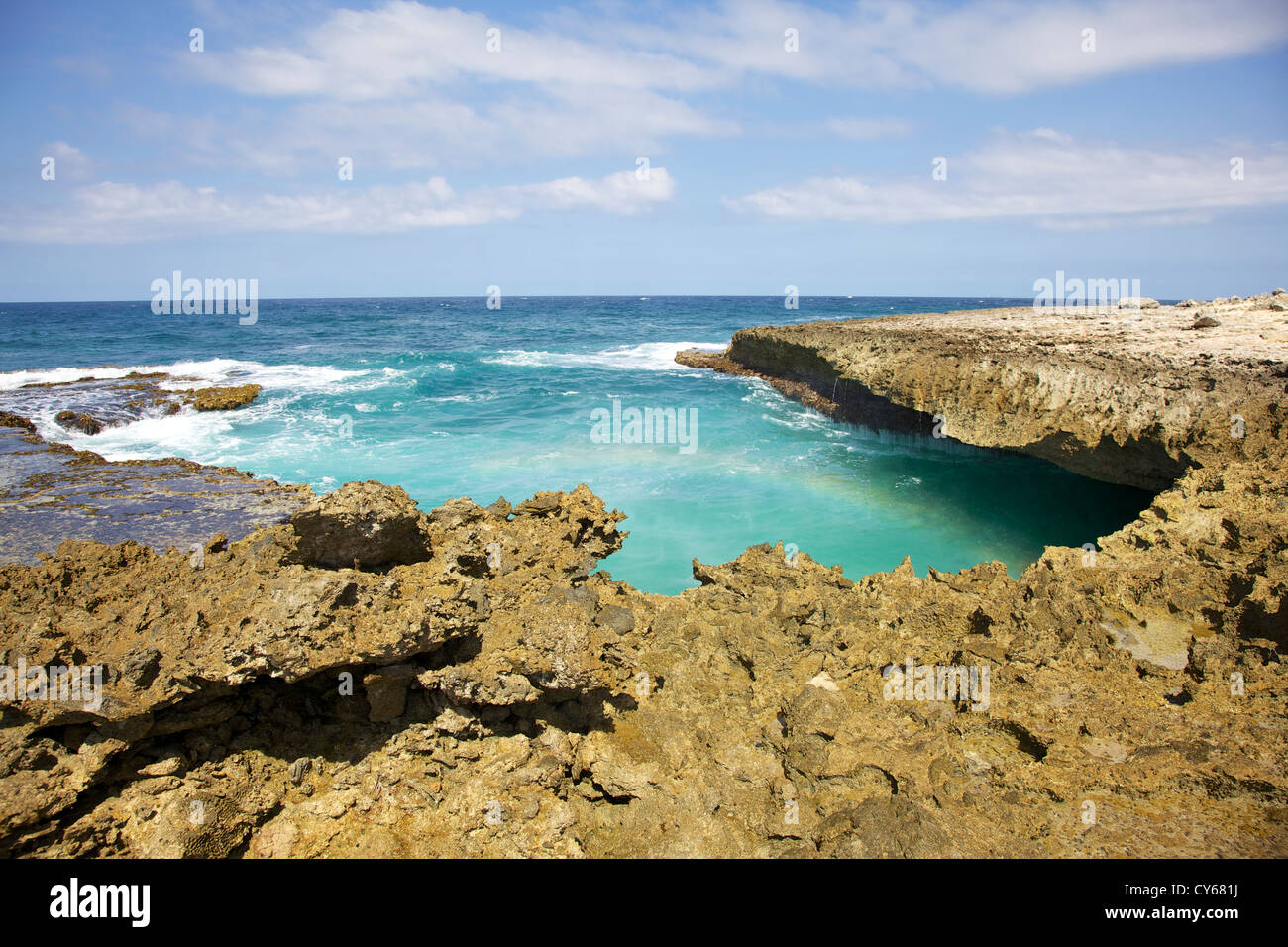 Aspre coste rocciose di Aruba con un arcobaleno contro le profonde acque blu Foto Stock