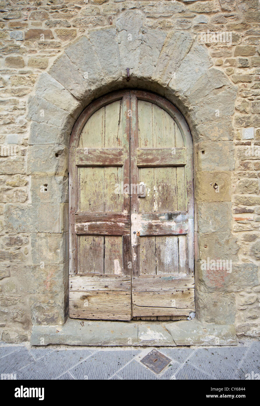 Sbiadita testurizzato porta di legno di un piccolo borgo medioevale della Toscana Foto Stock