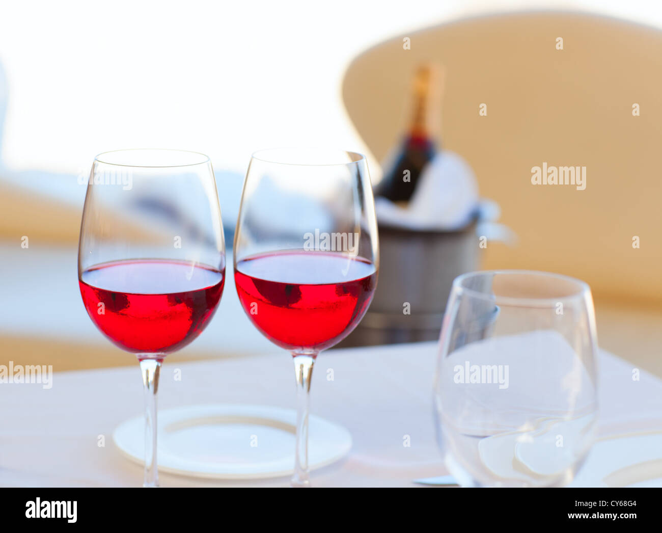 Due bicchieri di vino rosso e una bottiglia in background sul Secchiello per ghiaccio Foto Stock