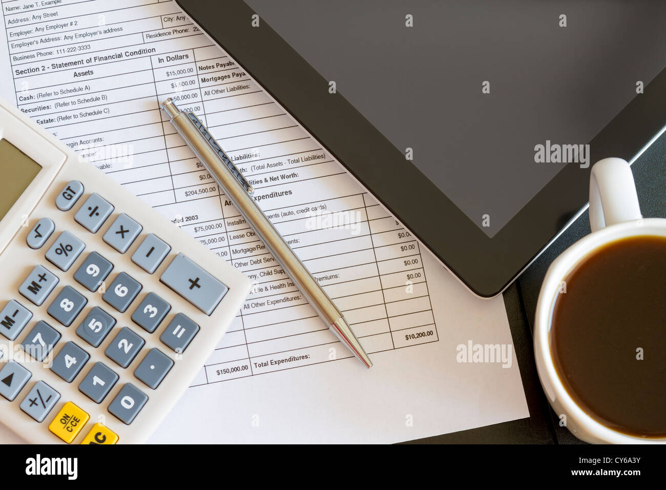 Ambiente di lavoro moderno con tavoletta digitale che mostra grafici e schema sullo schermo, caffè, penna e carta con i numeri. Foto Stock