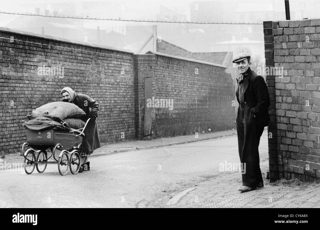 Donna che spinge un pram pieno di coke da Dudley gas Works in Spring Gardens Dudley West Midlands 1953. Uomo di lavoro Gran Bretagna 1950 lavoratore britannico nero paese di lavoro classe povera stile di vita povertà Foto Stock