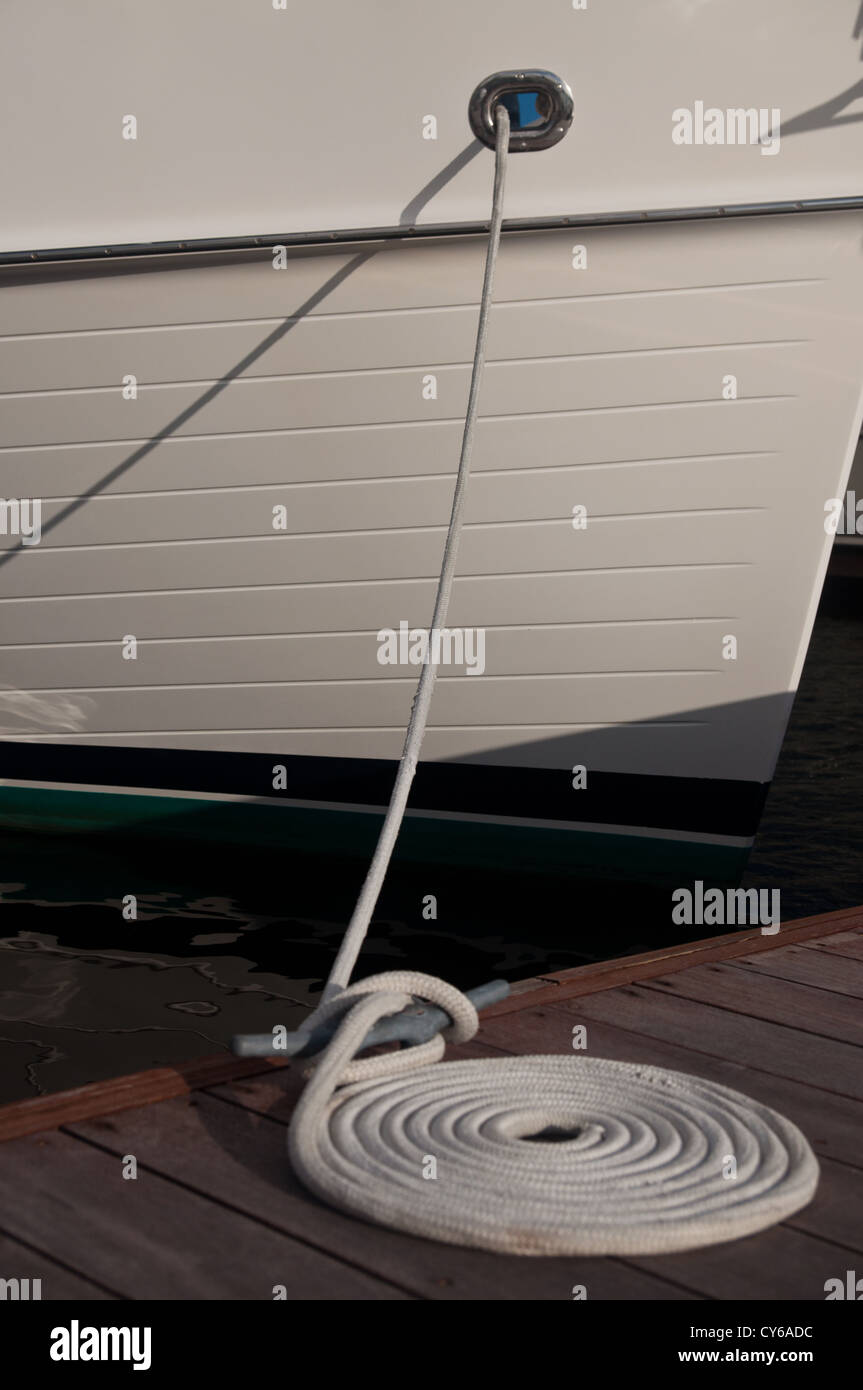 Barca bianca a un dock con un cavo a spirale di collegamento bianca sul dock Foto Stock