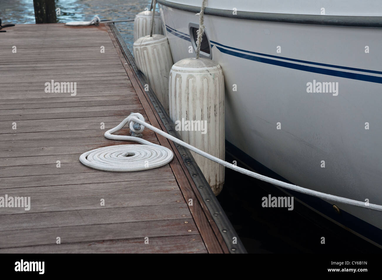 Barca bianca a un dock con un cavo a spirale di collegamento bianca sul dock Foto Stock