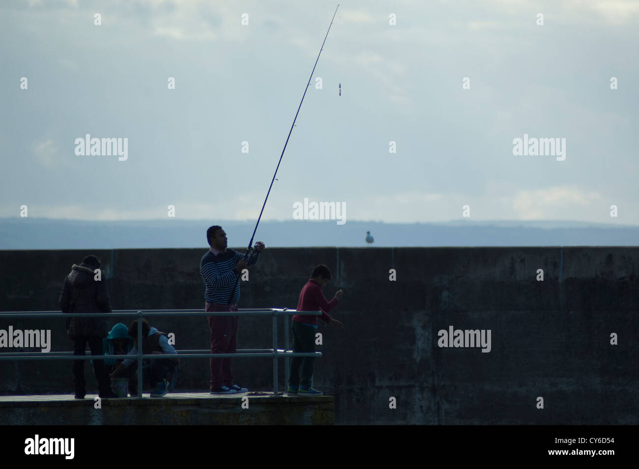 Un gruppo di persone di pesca off Aberystwyth harbour jetty. Foto Stock
