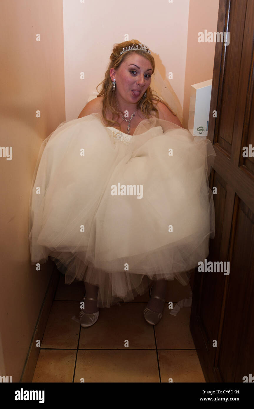 Modello rilasciato - bizzarro colpo di una sposa seduto su un wc a un matrimonio Foto Stock