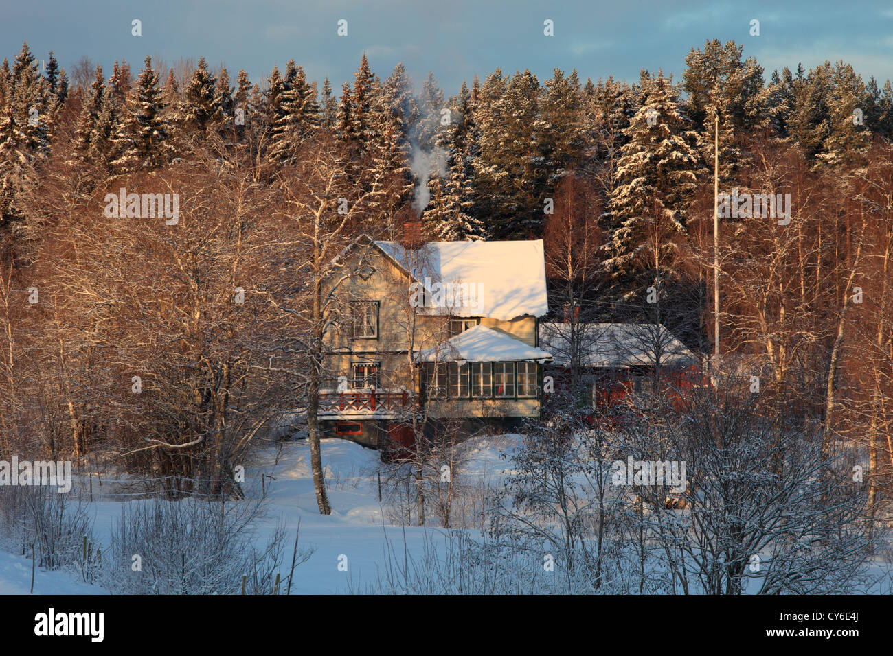 Il fumo è il curling dal camino di un giallo casa in legno in inverno. Foto Stock