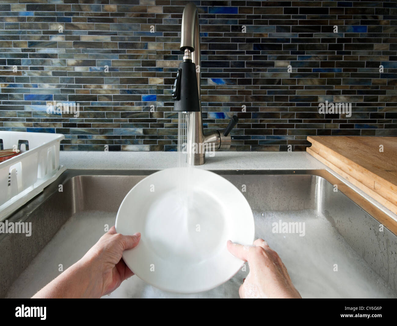 Le mani nel lavello con acqua e sapone lavare i piatti a mano Foto stock -  Alamy