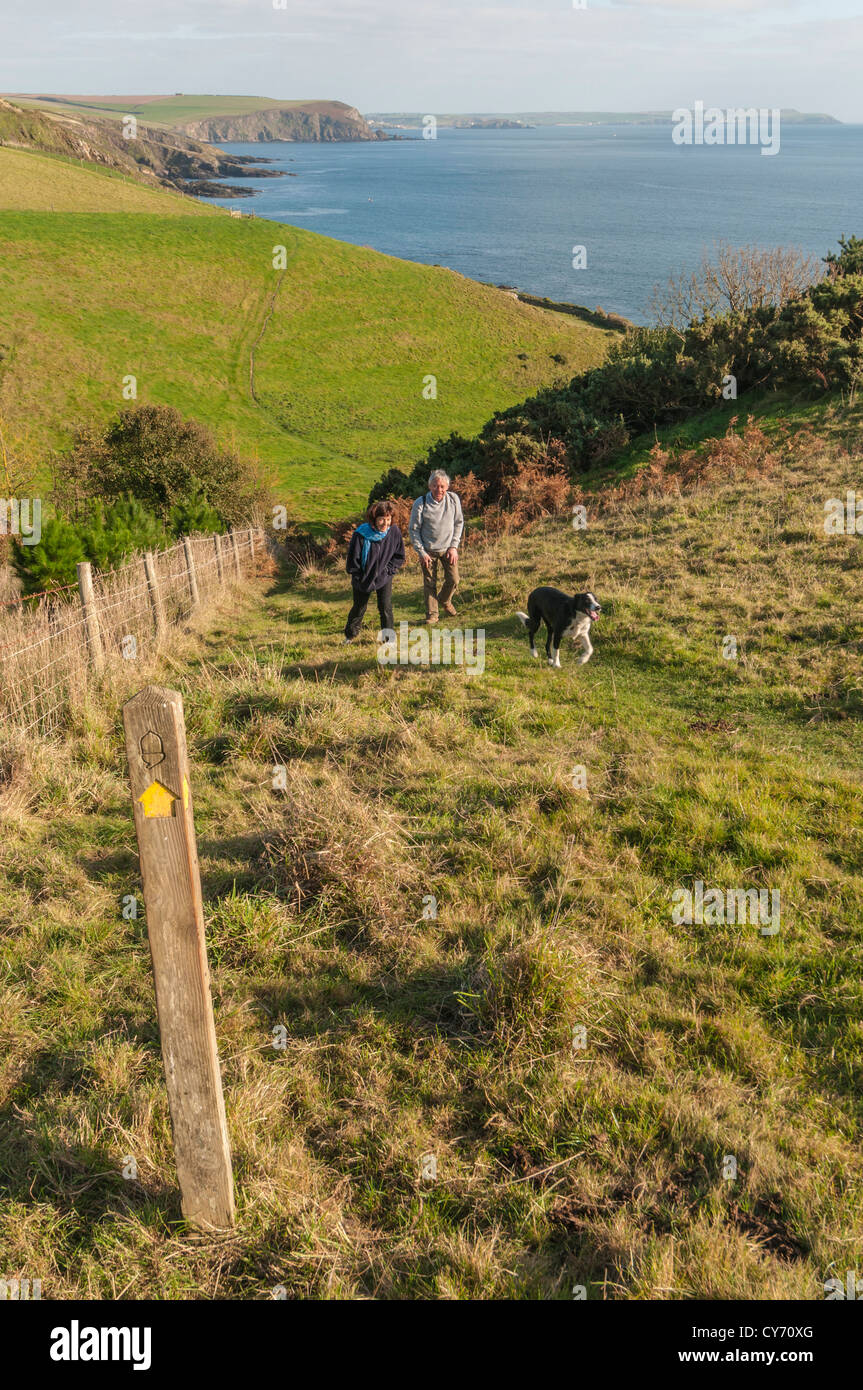 Una coppia e il loro cane a piedi il South Devon strada costiera ad est di Plymouth in una serata di tarda estate. Devon sud, Regno Unito Foto Stock