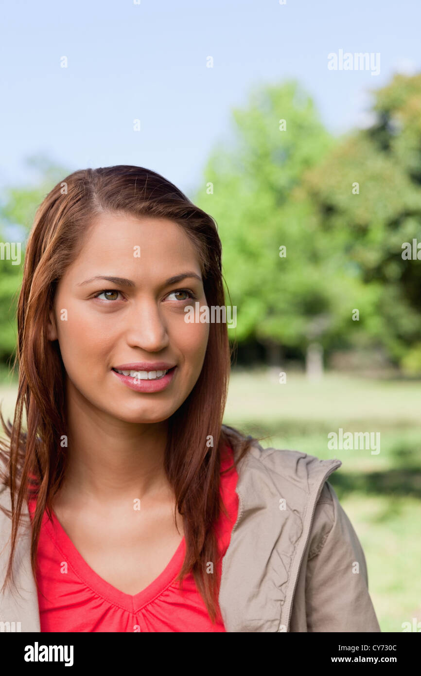 Donna che guarda verso il cielo con il sole che splende sul suo viso Foto Stock