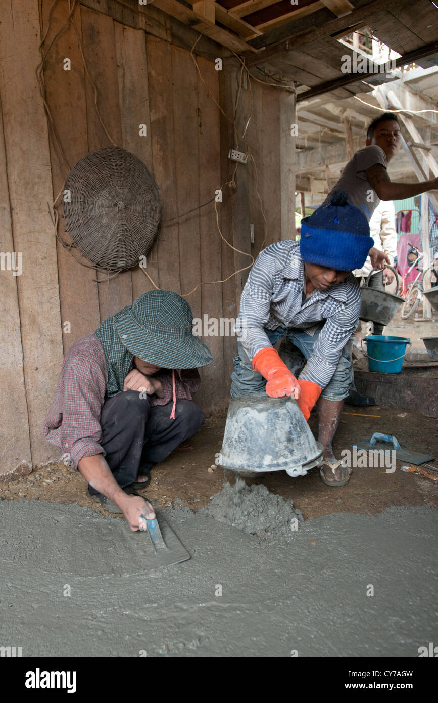 Un piccolo team di lavoratori edili deporre un nuovo pavimento in cemento O'Ambel village, Sisophon, Cambogia Foto Stock