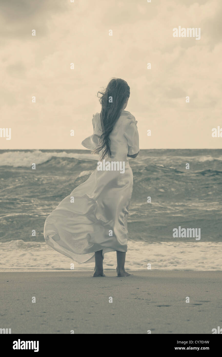 Una ragazza in un abito bianco è in piedi da sola la wild, mare mosso Foto Stock