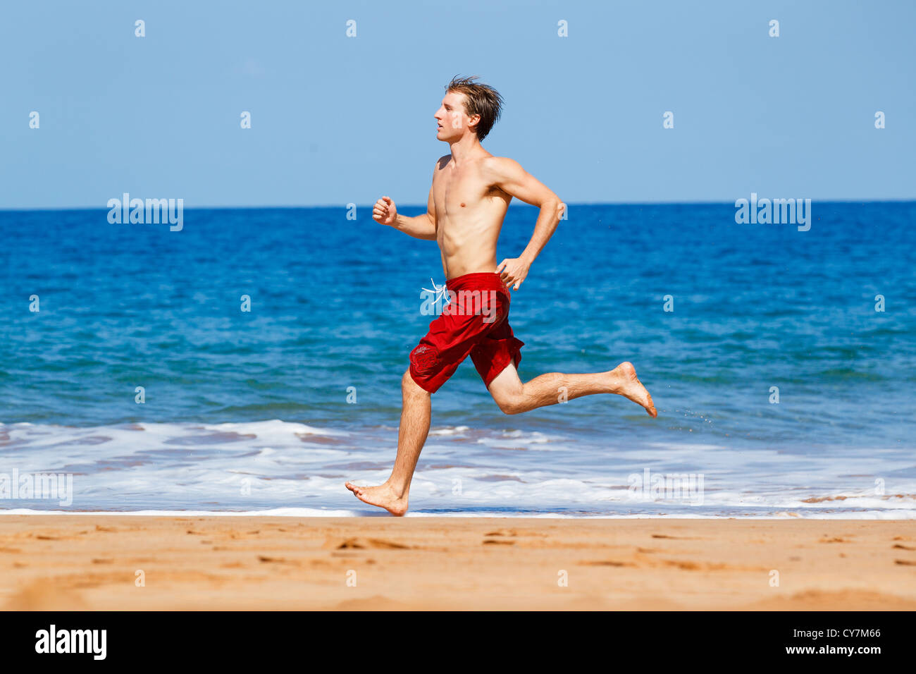 Montare fisicamente uomo correre sulla spiaggia alle Hawaii Foto Stock