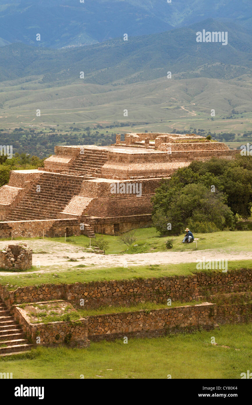 Uomo ispanico si siede vicino a piramide a Monte Alban sito archeologico, Oaxaca, Messico Foto Stock