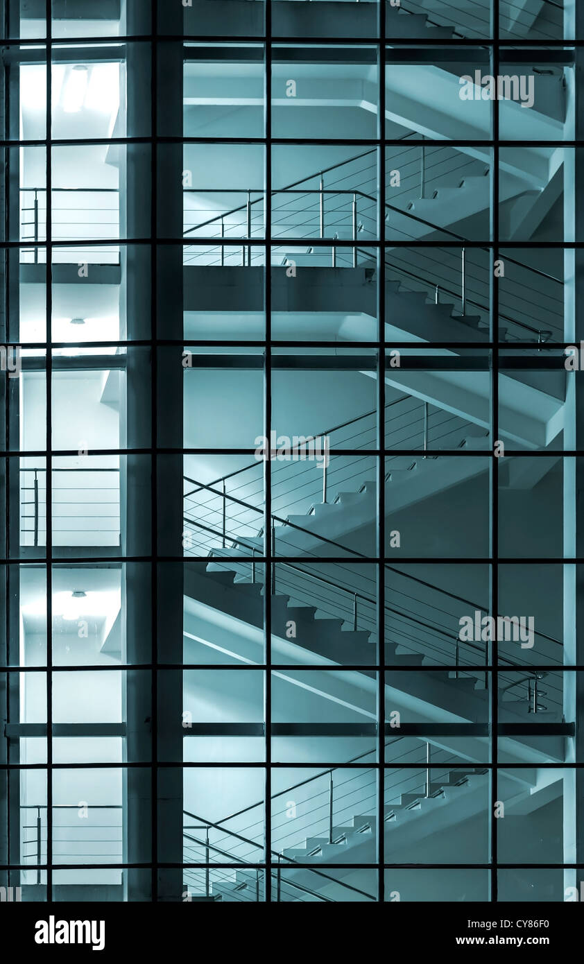 Edificio moderno con facciata scalinata dietro una parete di vetro trasparente Foto Stock