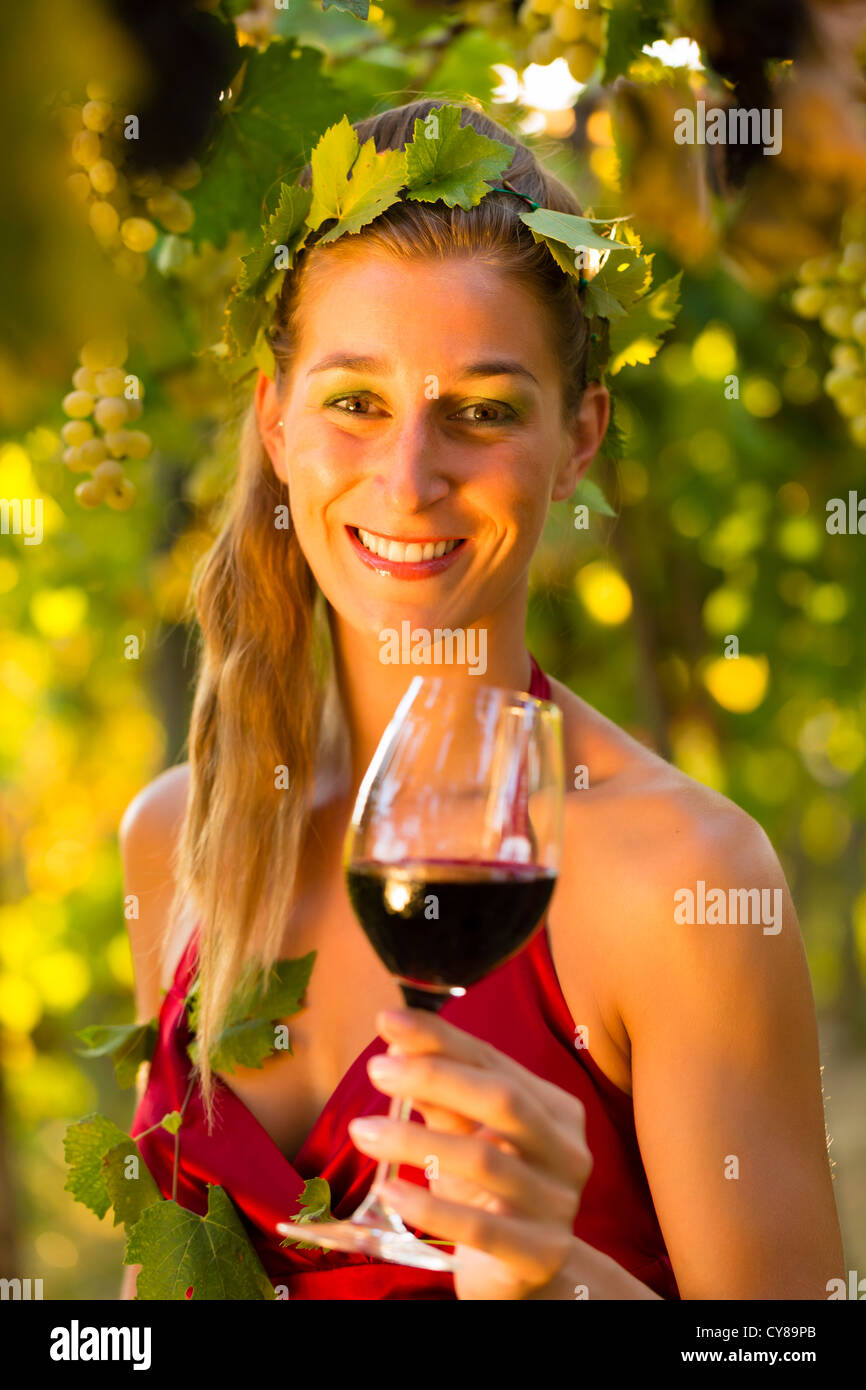 Donna con un bicchiere di vino in vigna con il sole splendente, ella è la regina del vino Foto Stock