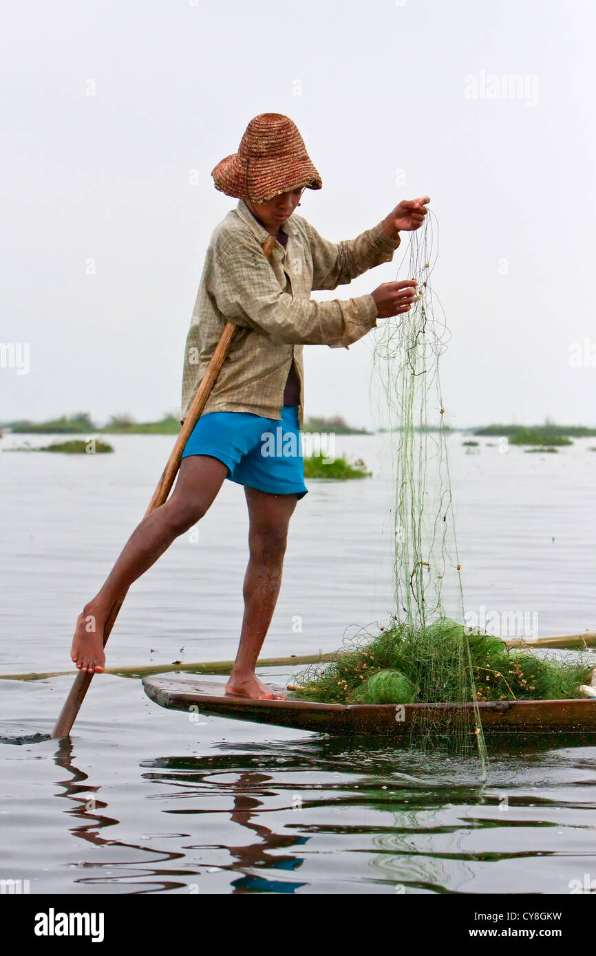 Myanmar Birmania. Pescatore Intha prepara il suo netto, in equilibrio su una gamba, nello stile consueto per Lago Inle, Stato di Shan. Foto Stock