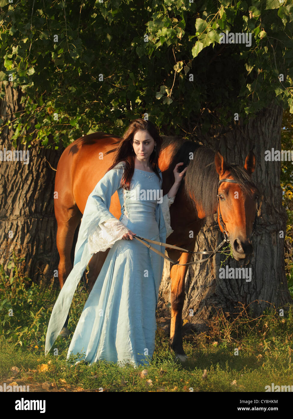 La donna in un bellissimo vecchio stile medievale abito passeggiate a cavallo nei boschi di colore giallo Foto Stock