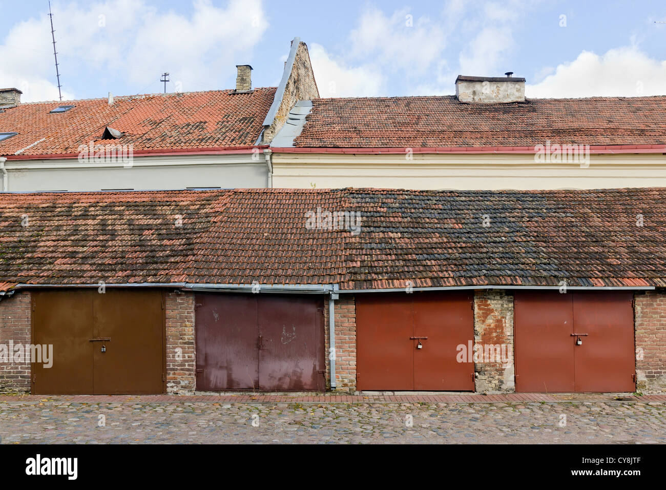 Garage in metallo la produzione di massa di porte. I garage sono situato nel vecchio antico edificio di mattoni rossi con un'argilla tetto di tegole. La combinazione di p Foto Stock