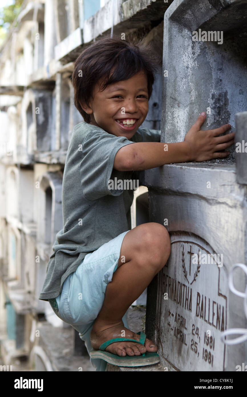 I bambini la riparazione di lapidi in preparazione per tutti i Santi/Anime giorno,cimitero Carreta;Cebu;Filippine Foto Stock