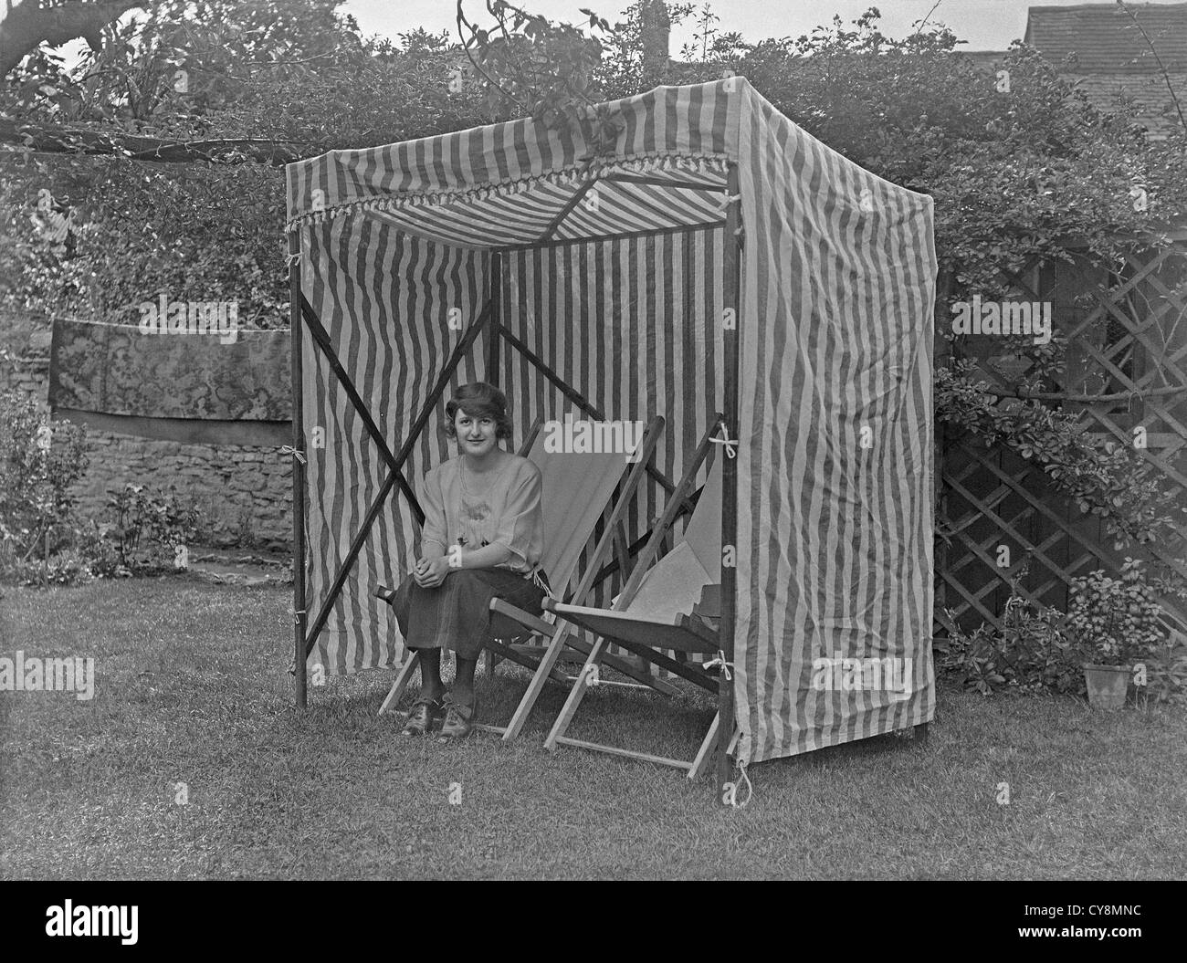 Donna rilassante nel suo giardino sul retro sotto il riparo di un gazebo, c. 1930 Foto Stock