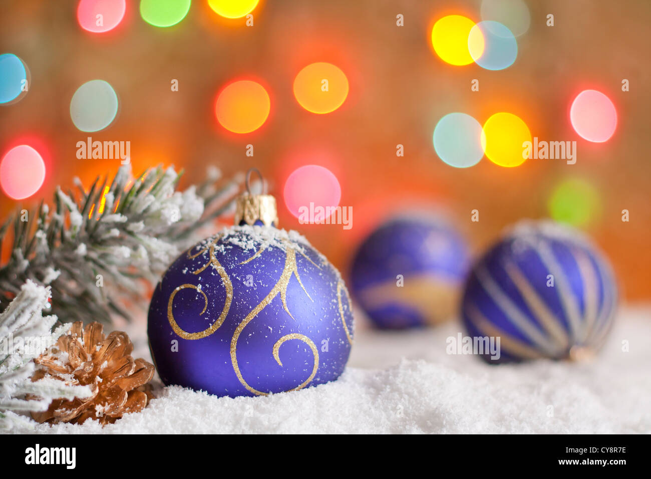 Baubles di Natale sulla neve contro sfocato sfondo colorato Foto Stock