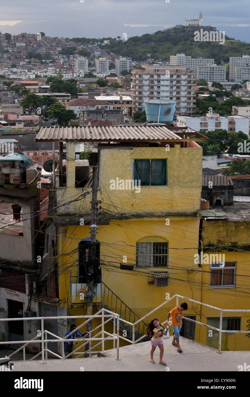 Vista dalla Baiana hill nel Complexo do Alemão favela, con la Penha Church in background e di Rio de Janeiro in Brasile Foto Stock
