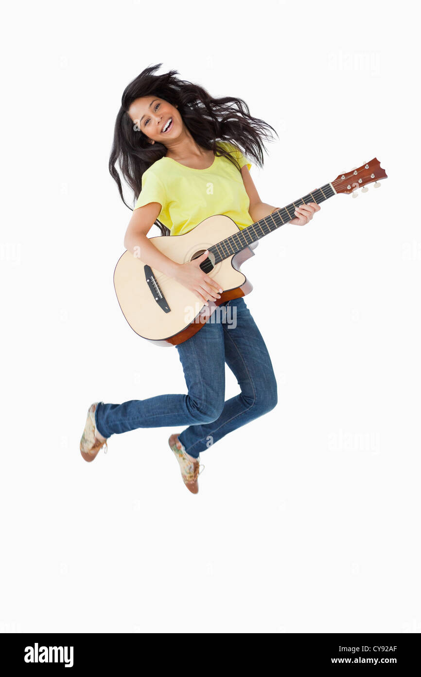 Giovane donna in possesso di una chitarra mentre jumping Foto Stock