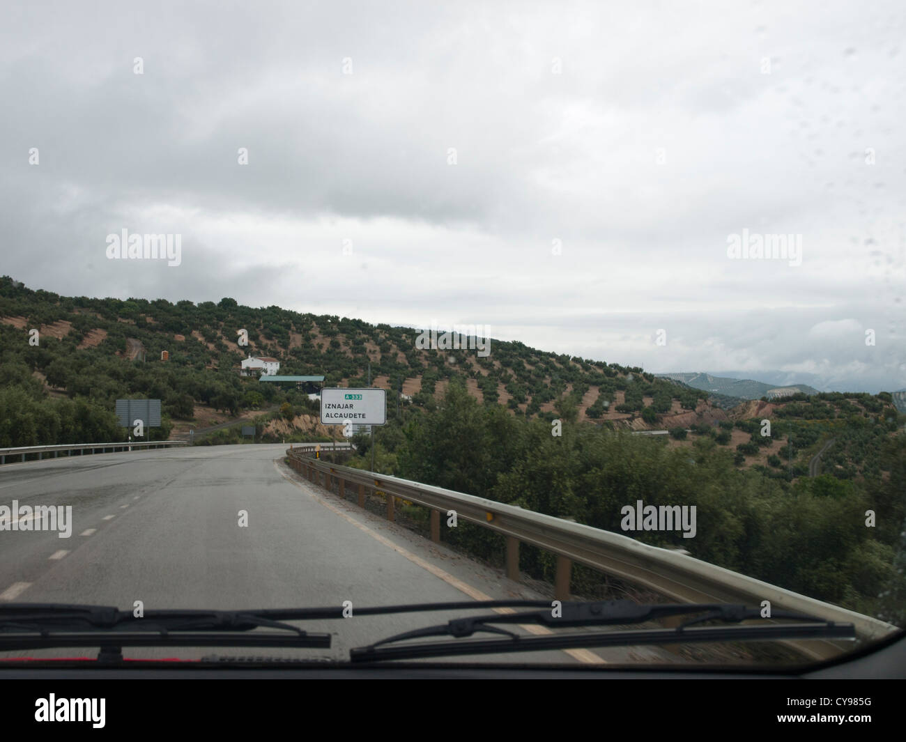 Un giorno di pioggia la marcia su strade in colline andaluso, vista dall'interno di una vettura oliveti road e tergicristalli Foto Stock