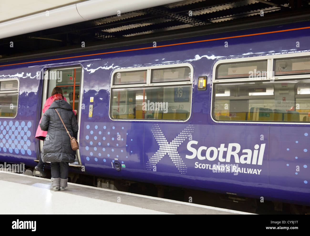 Due donne di salire a bordo di un treno Scotrail; livello inferiore, la stazione di Queen Street, Glasgow, Scotland, Regno Unito Foto Stock