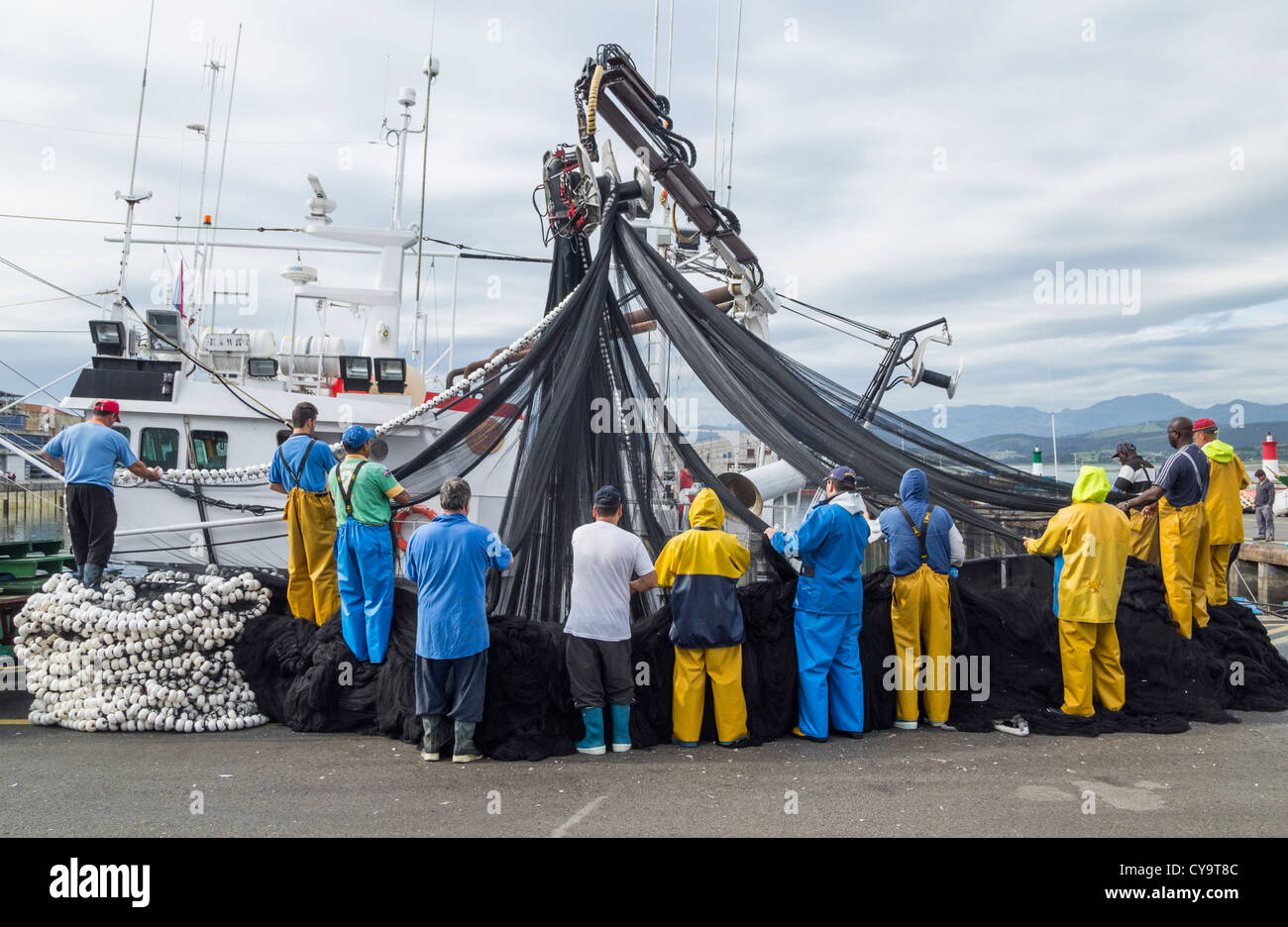 Equipaggio con reti da pesca nel porto di Santoña, Cantabria, SPAGNA Foto Stock